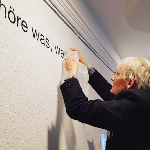 Timm Ulrich bringt den Schriftzug „Höre was, was …“ mit Klebebuchstaben
an die Wand an.